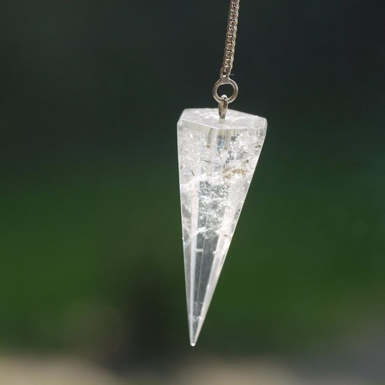 Crystal healing A quartz pendulum is suspended in the air.