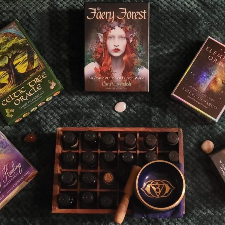 Tarot readings Oracle cards in a semi circle surrounding a box of essential oils and a crown chakra singing bowl.